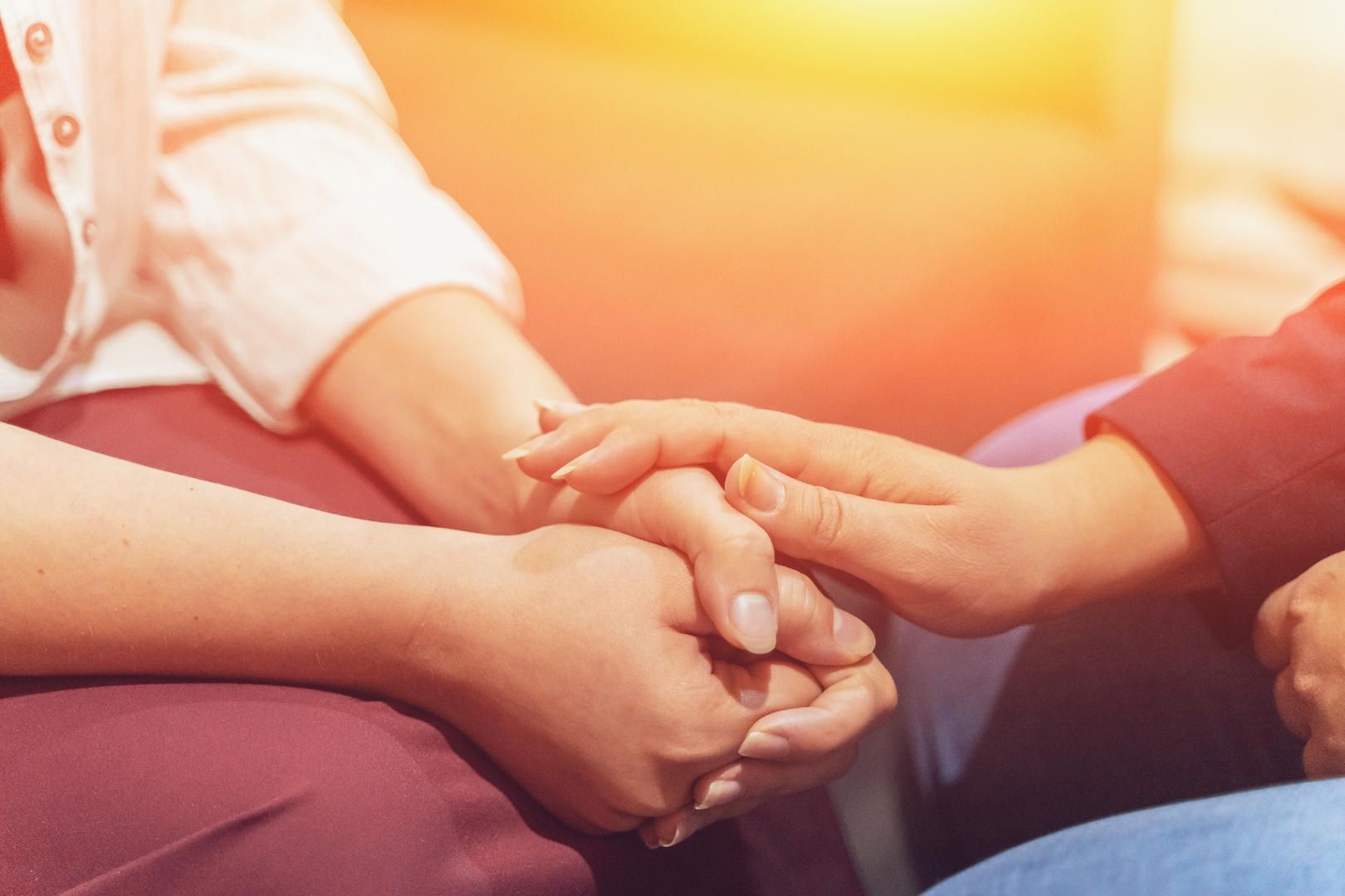A group of people are holding hands while sitting on a couch.