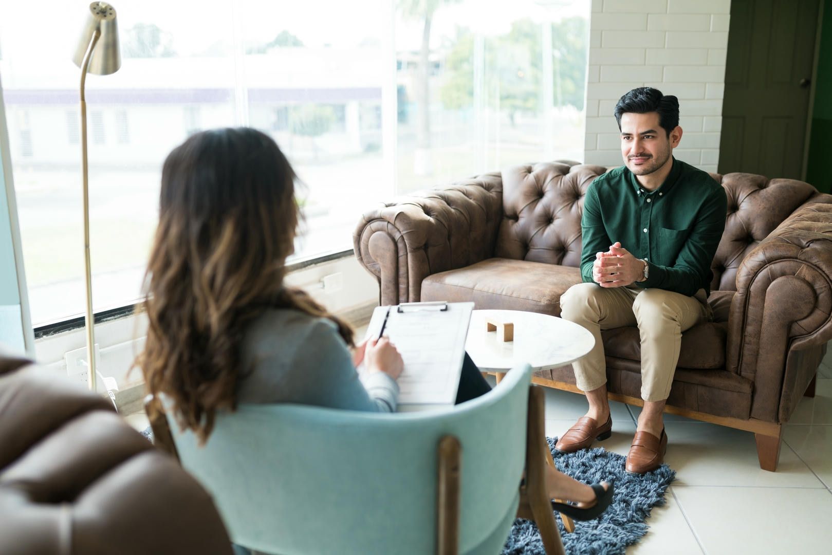 A man is sitting on a couch talking to a woman.