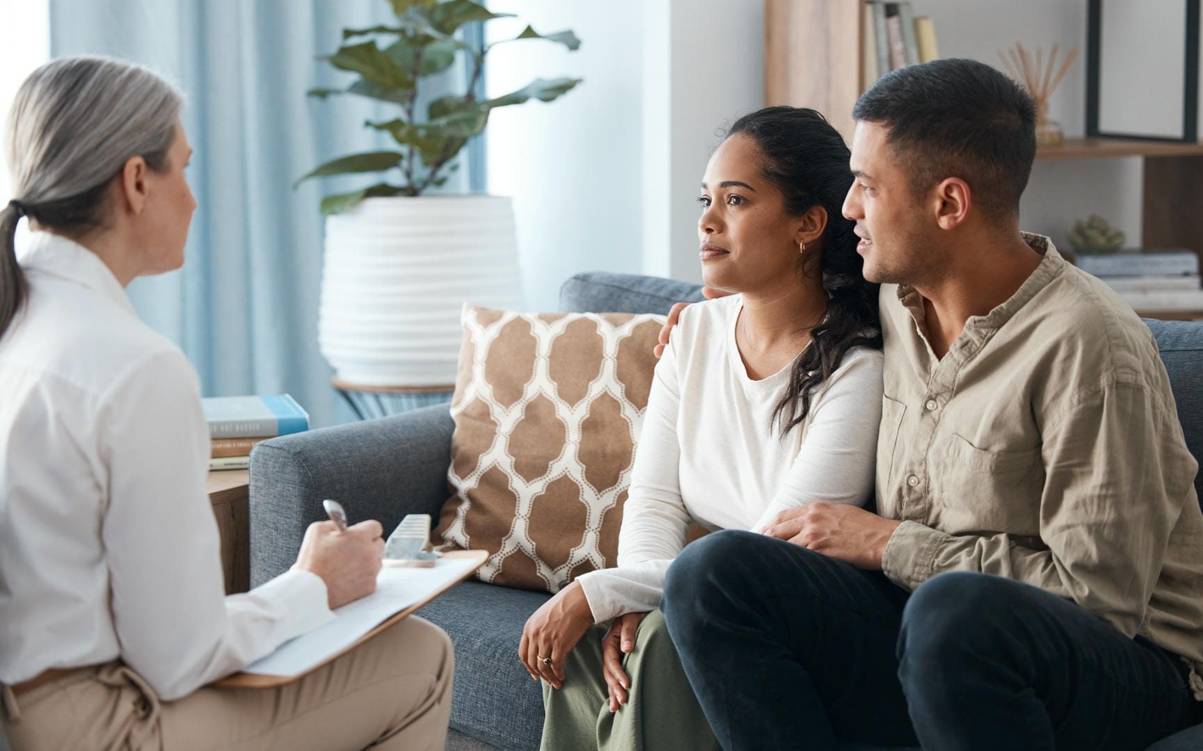 A man and a woman are sitting on a couch talking to a woman.