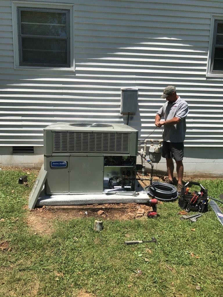 Technician installing an AC unit by David Brown Heating & Cooling.