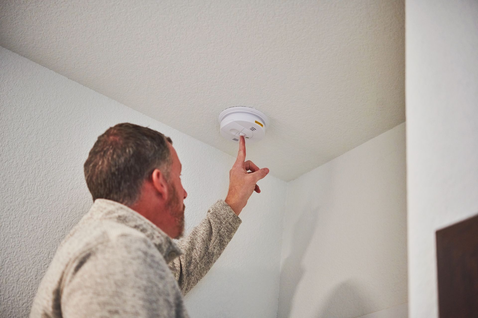 David Brown technician inspecting smoke alarm in Tennessee home during winter safety maintenance.