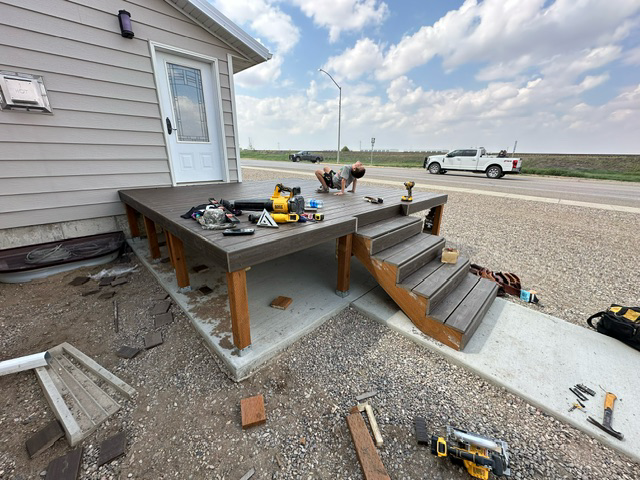 A man is working on a deck in front of a house