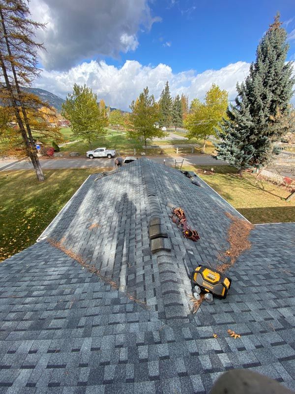 A person is standing on top of a roof with tools on it.