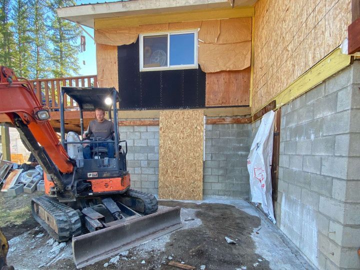 man handling a construction equipment outside of a newly renovated house