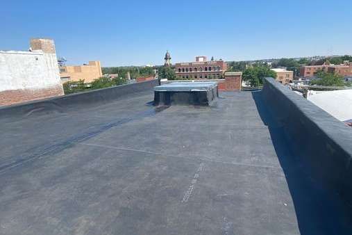 A rooftop with a chimney on it and a view of a city.