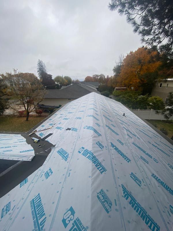 The roof of a house is being covered with a roofing material.
