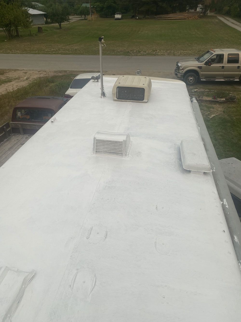 A white truck is parked on the roof of a rv.
