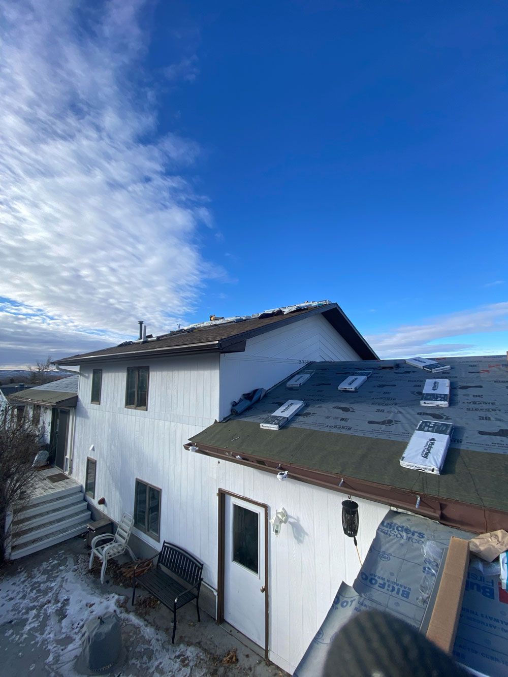 A white house with a green roof and a blue sky in the background.
