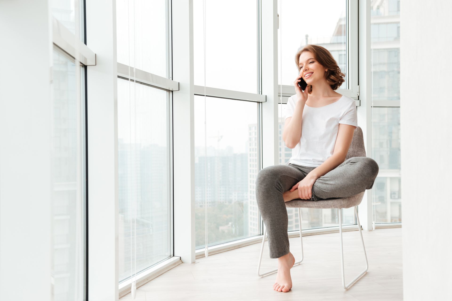 A woman is sitting on a chair talking on a cell phone.