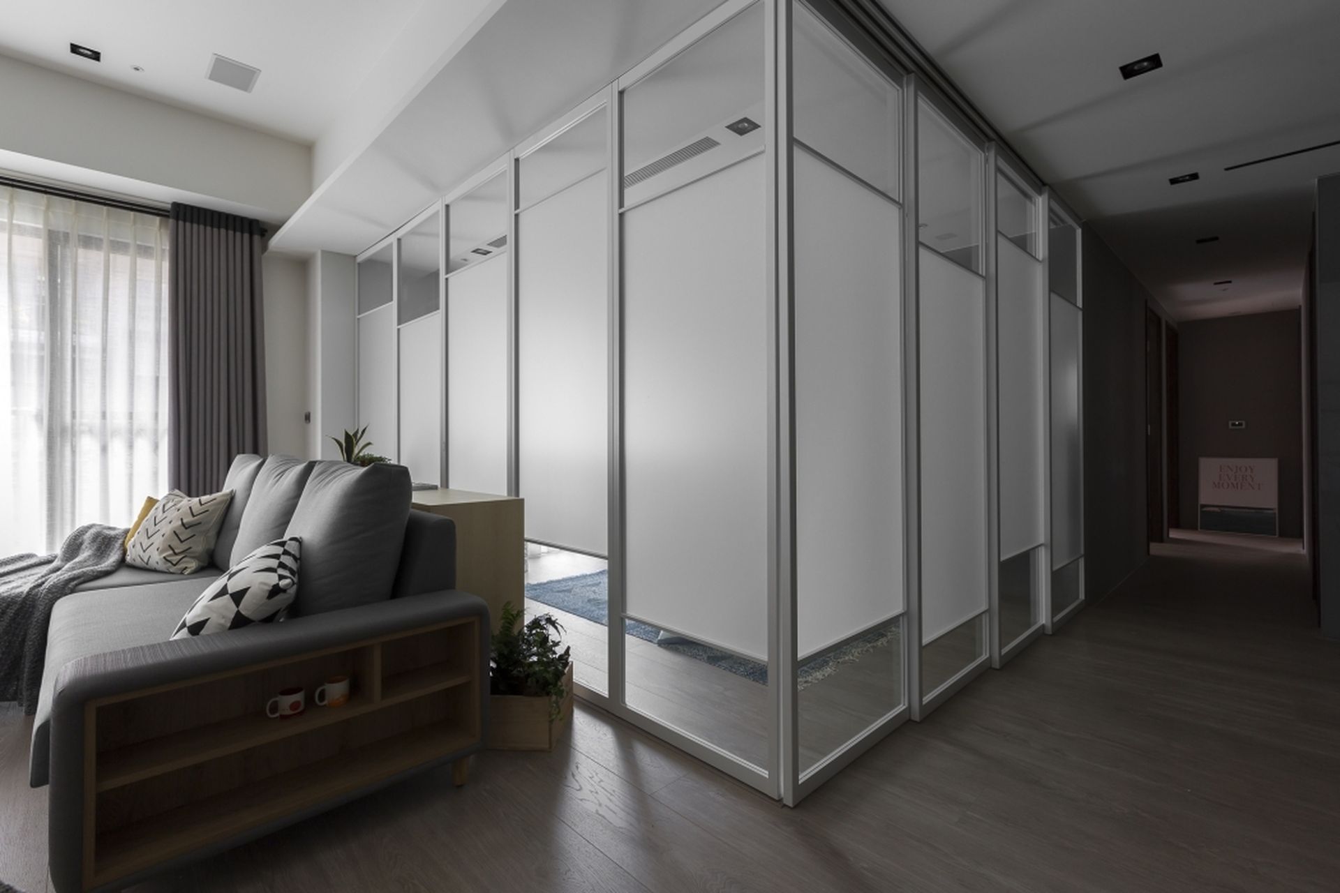A living room with a couch and a hallway leading to a bedroom.
