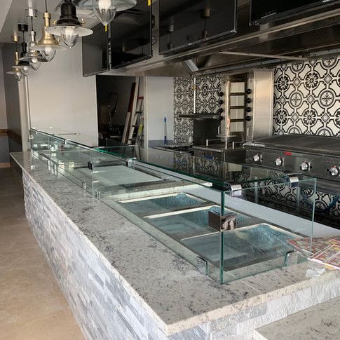 A kitchen with a long counter and a glass display case.