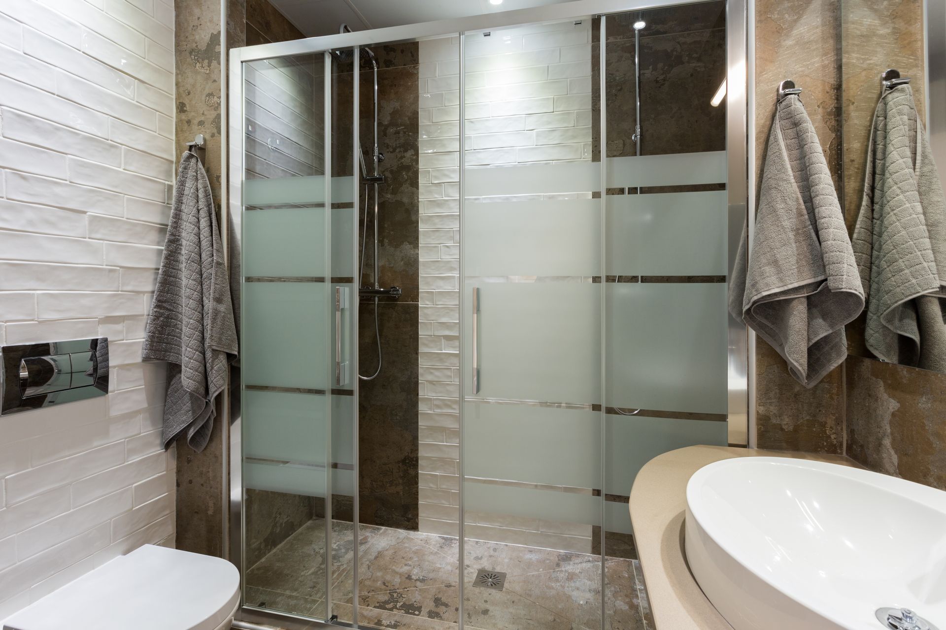 A bathroom with a toilet , sink and shower stall.