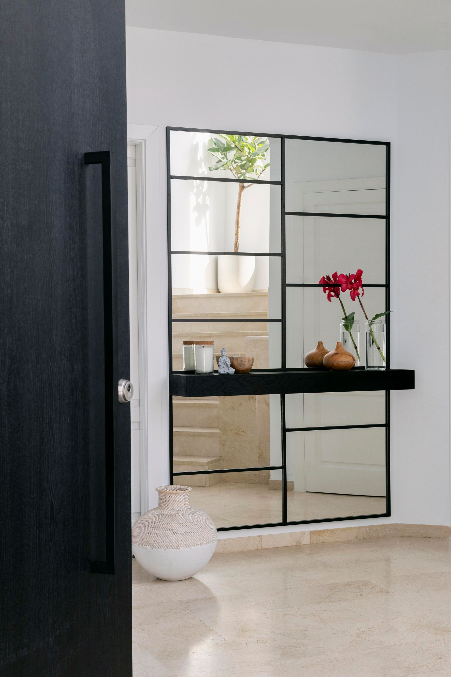 A hallway with a large mirror and a black door