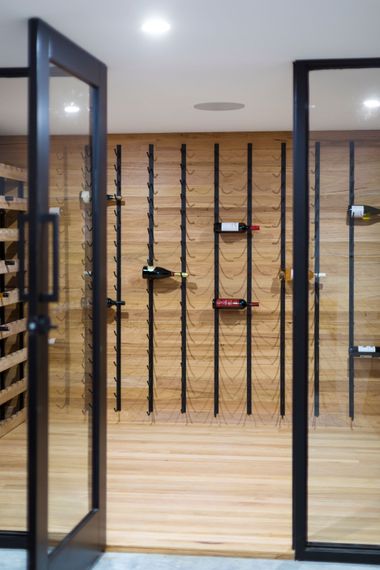 A wine cellar with a glass door and wooden shelves