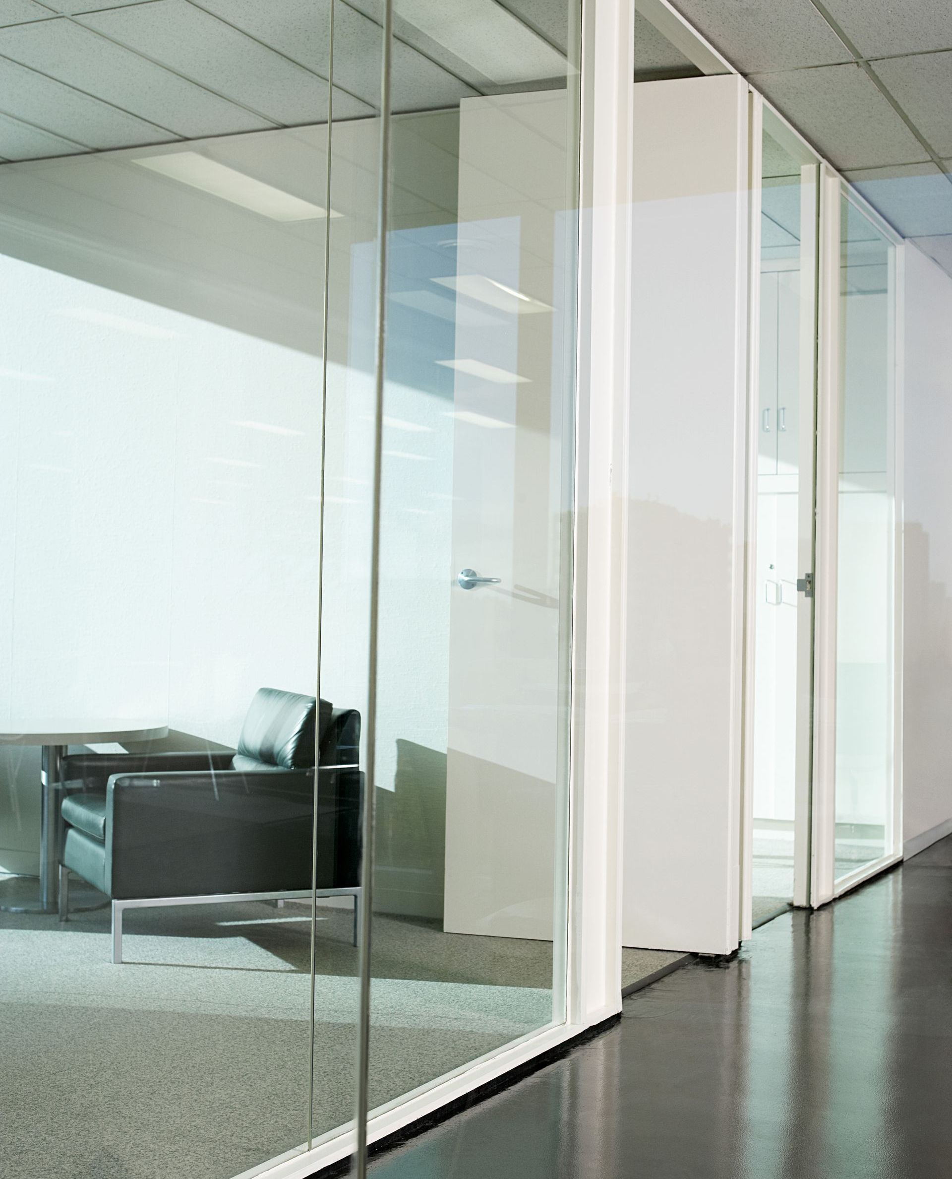 A hallway with glass walls and a chair in the background