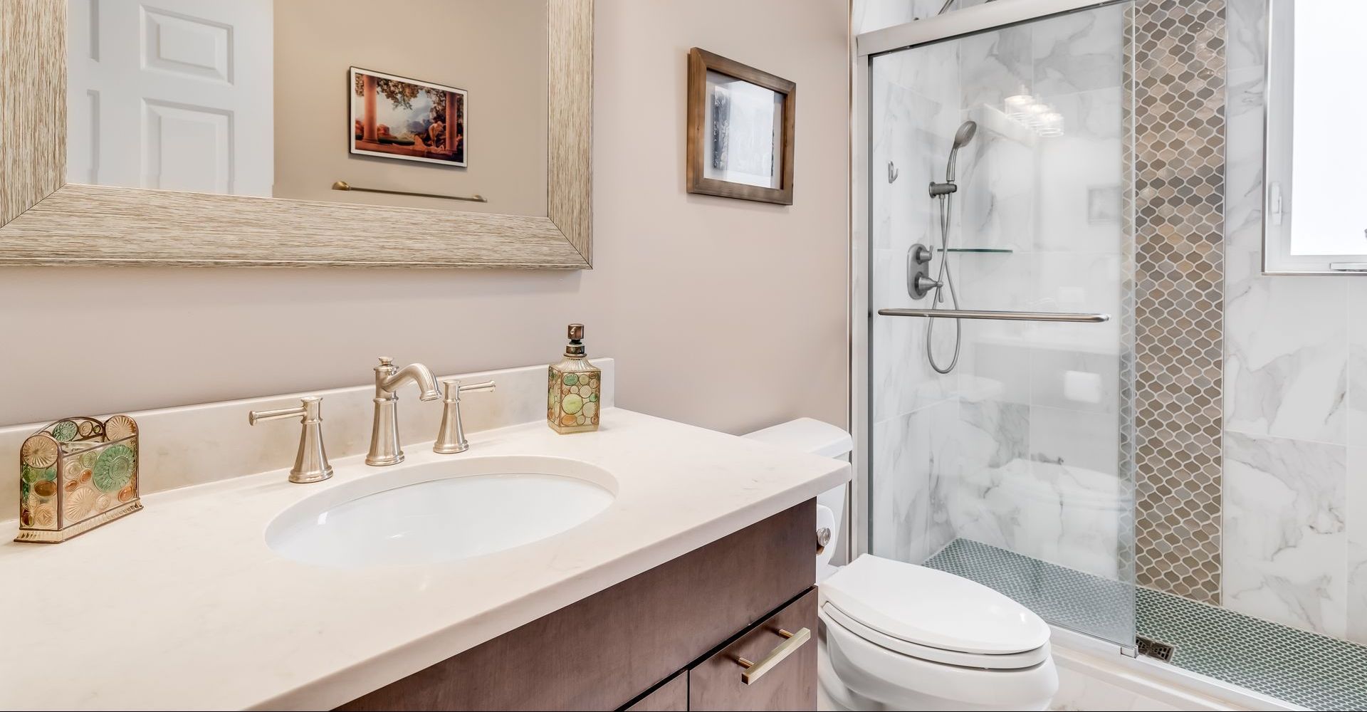 A bathroom with a sink , toilet , shower and mirror.