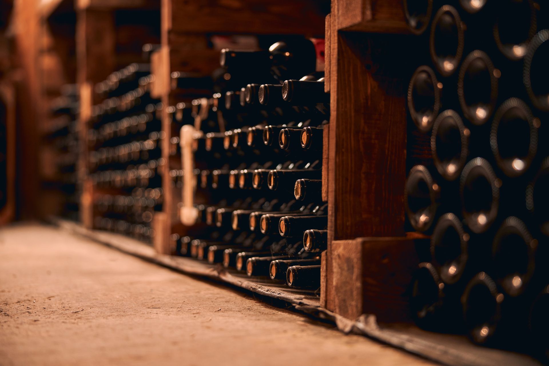 A row of wine bottles stacked on top of each other in a wine cellar.