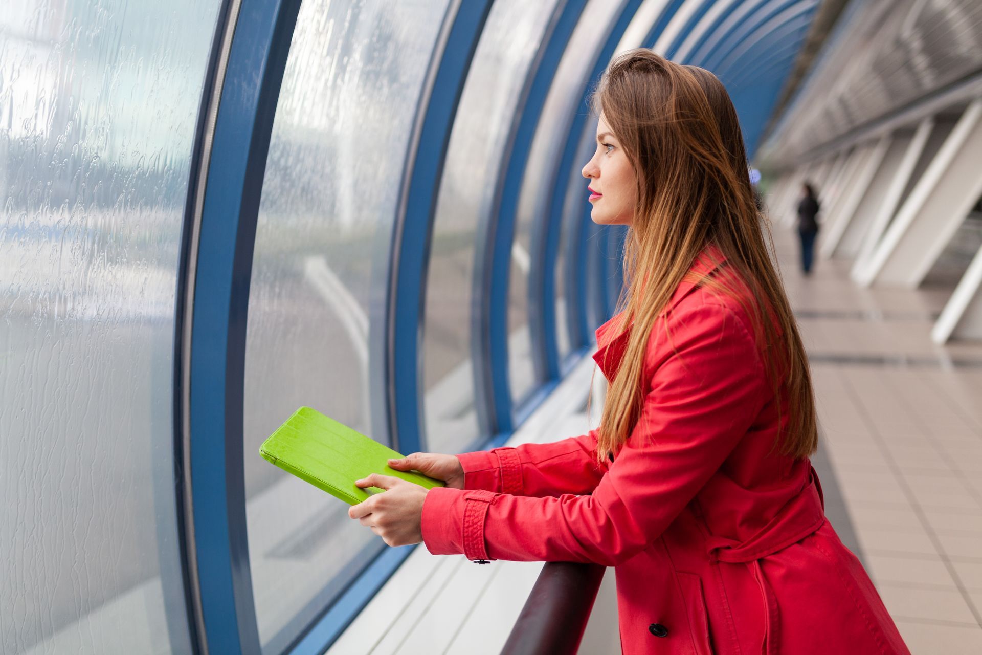 A woman in a red coat is looking out of a window in a commercial building.