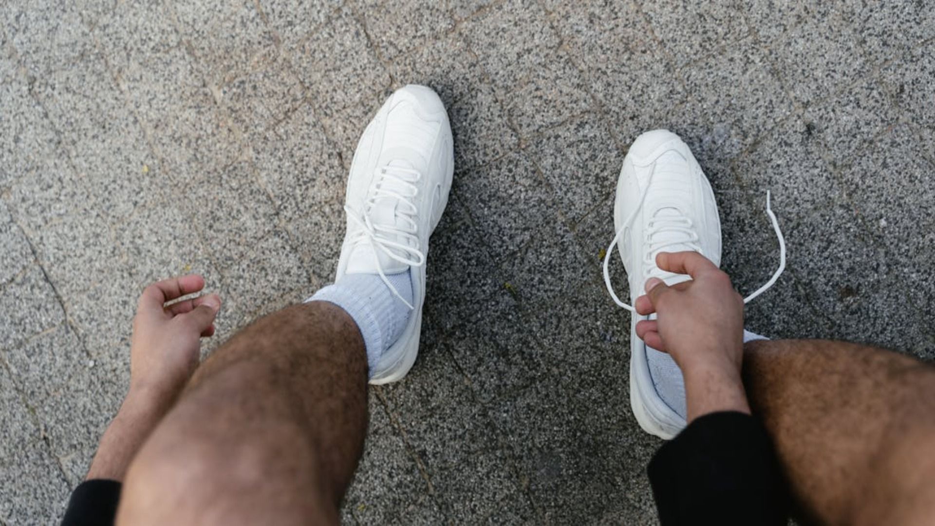 Una persona se está atando los zapatos en el suelo.