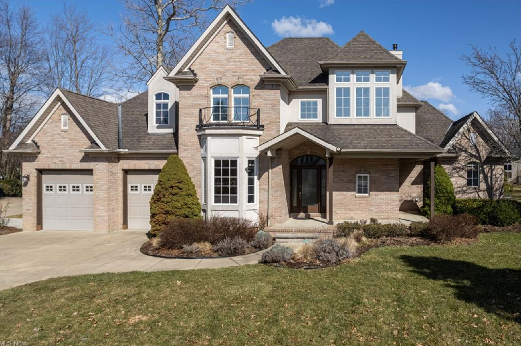 A large brick house with a gray roof and two garage doors.