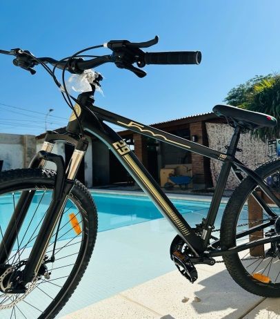 Una bicicleta negra y dorada está estacionada junto a una piscina.