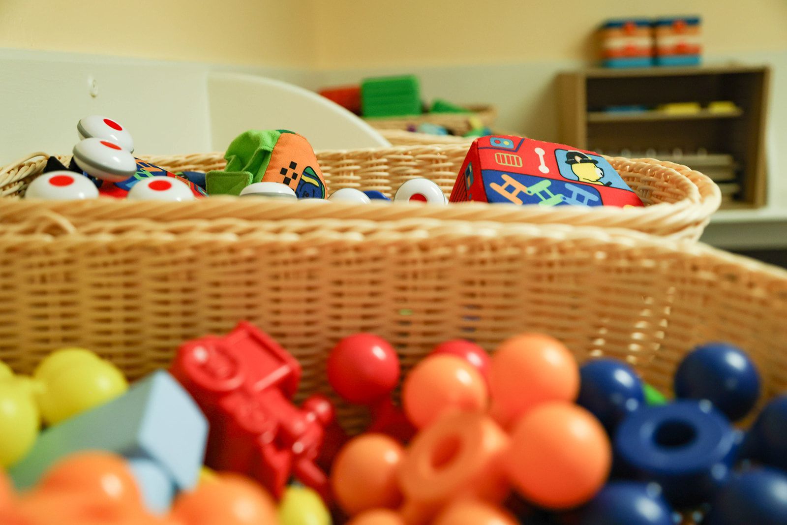 Wicker baskets filled with colorful toys in a well-lit room, possibly a playroom or classroom.