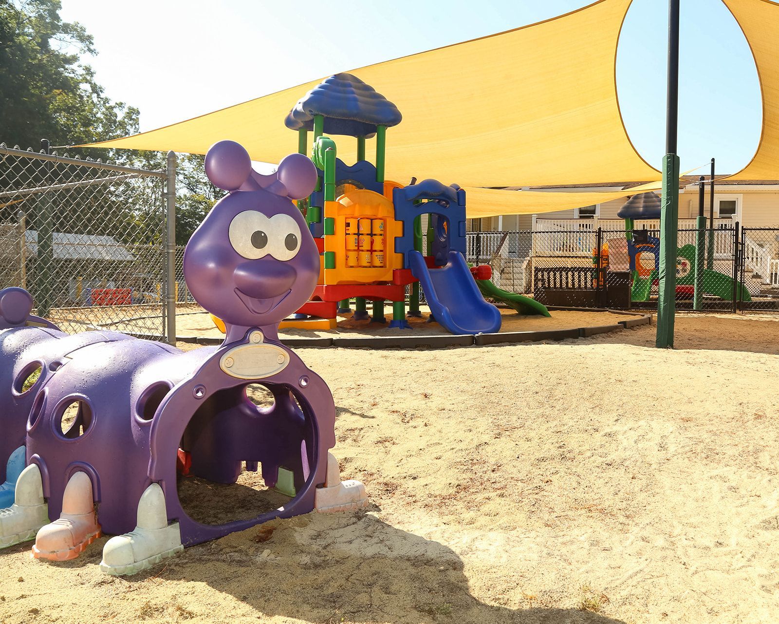 Purple caterpillar tunnel, playground with slide and structures, shaded area.