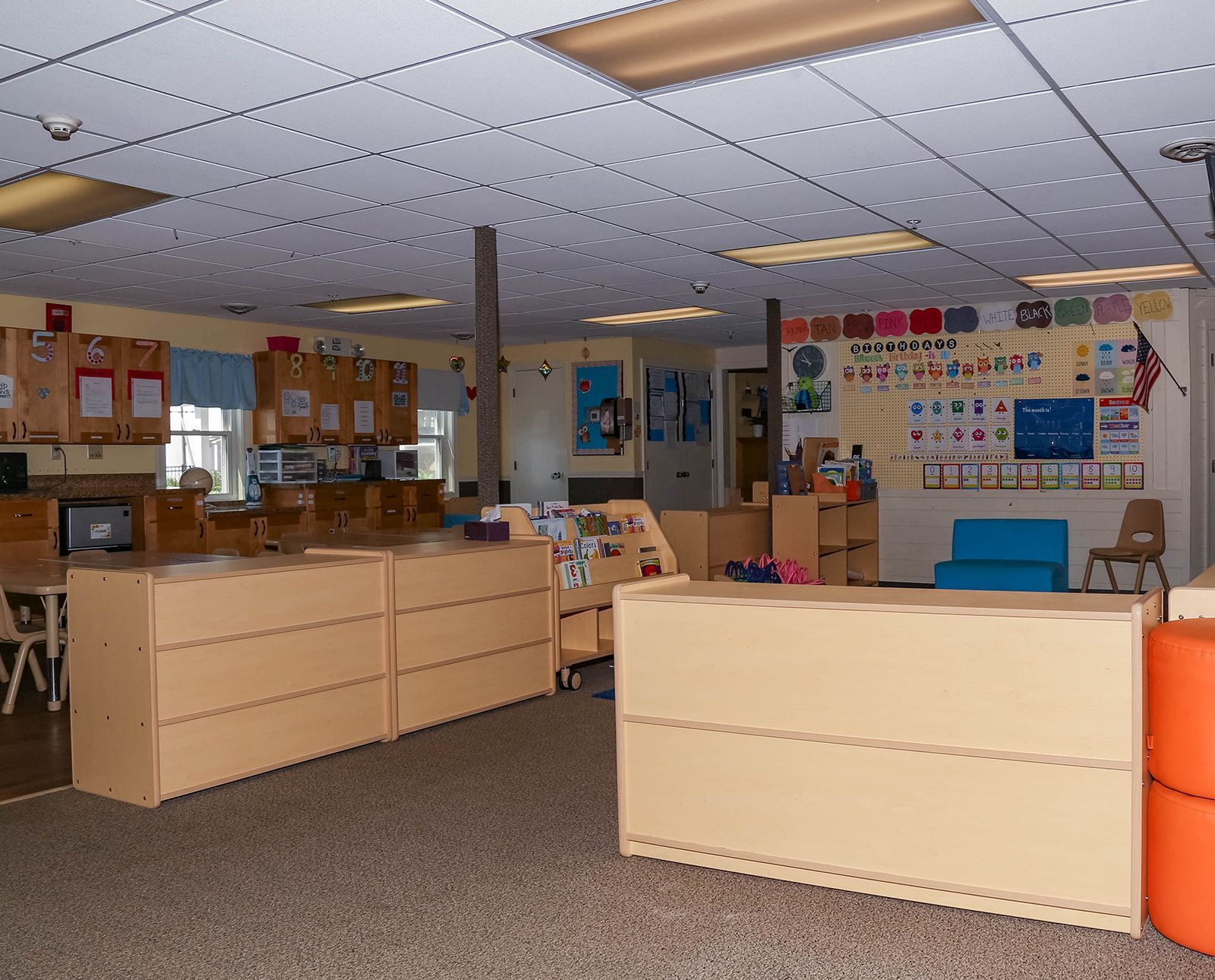 Classroom with beige cabinets, tables, and learning displays on walls.