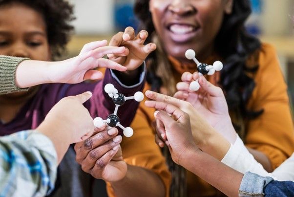 Students and teacher looking at molecule models
