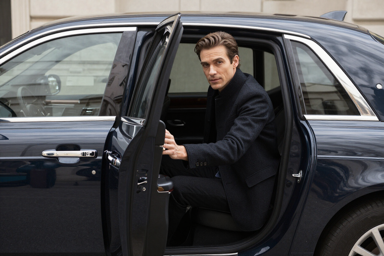 Professional driver holding open the door of a luxury saloon car