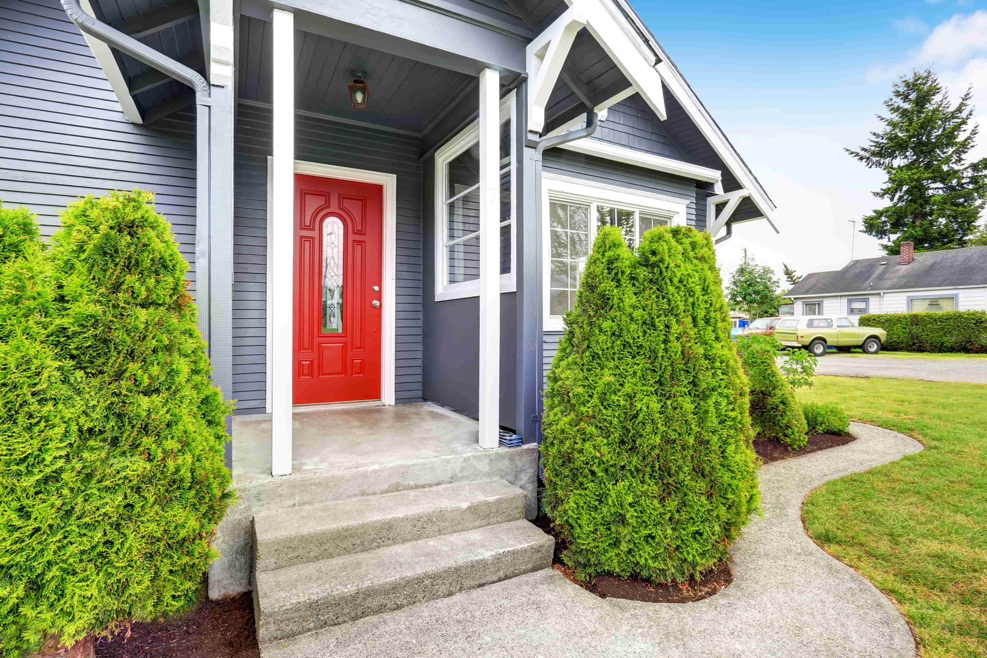 A gray house with a red door and a porch.