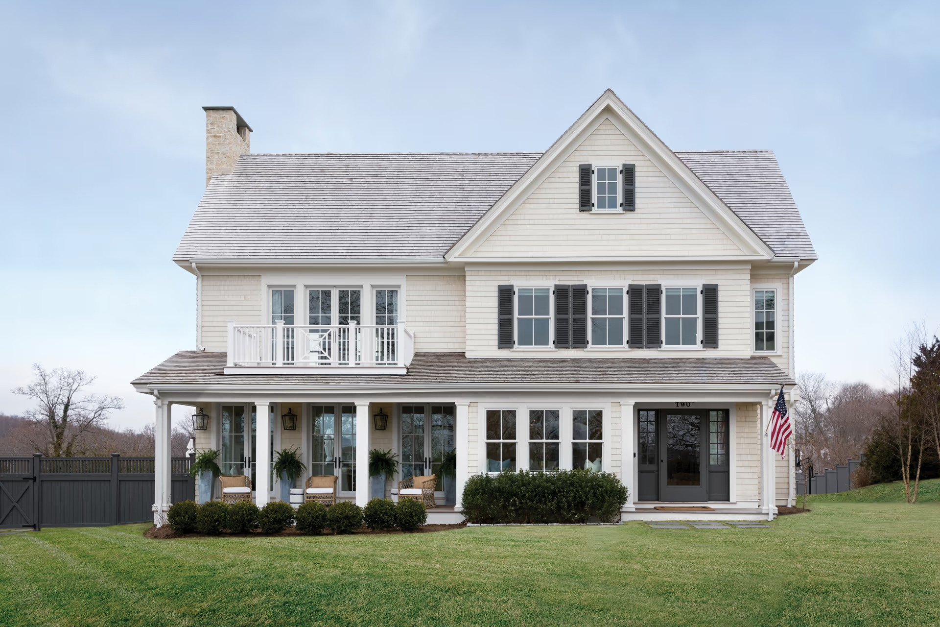 A large white house with black shutters and a large porch.