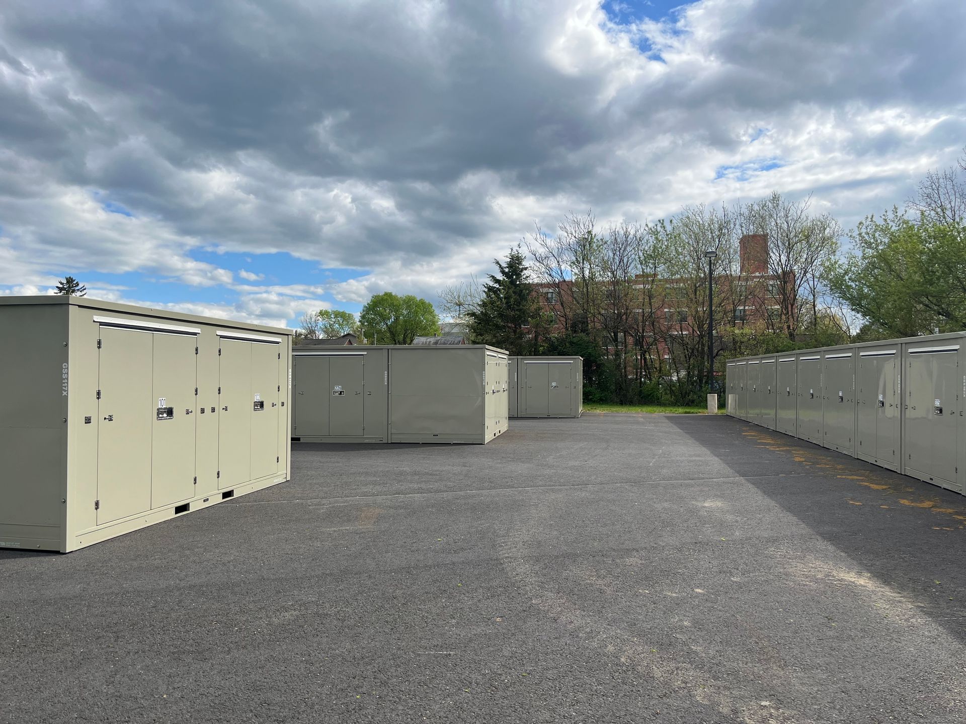 A row of white containers are lined up in front of a building.
