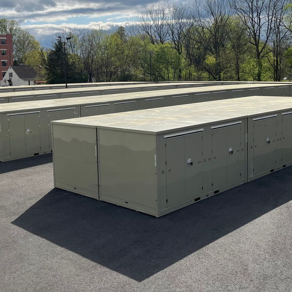 A row of self storage lockers are lined up in a parking lot.