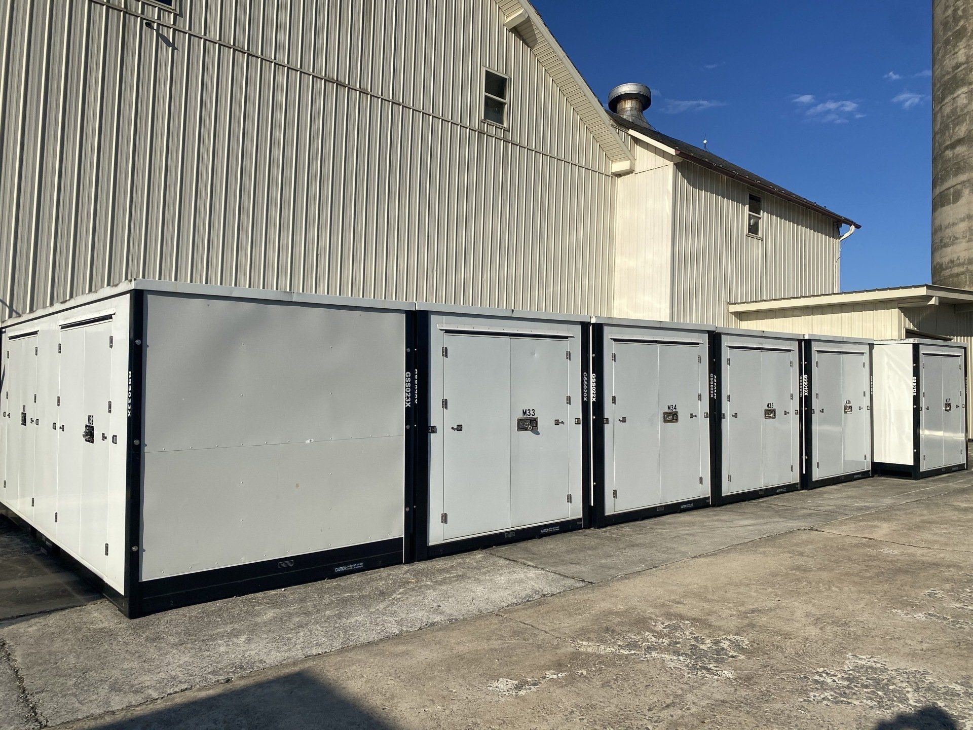 A row of white containers are lined up in front of a building.
