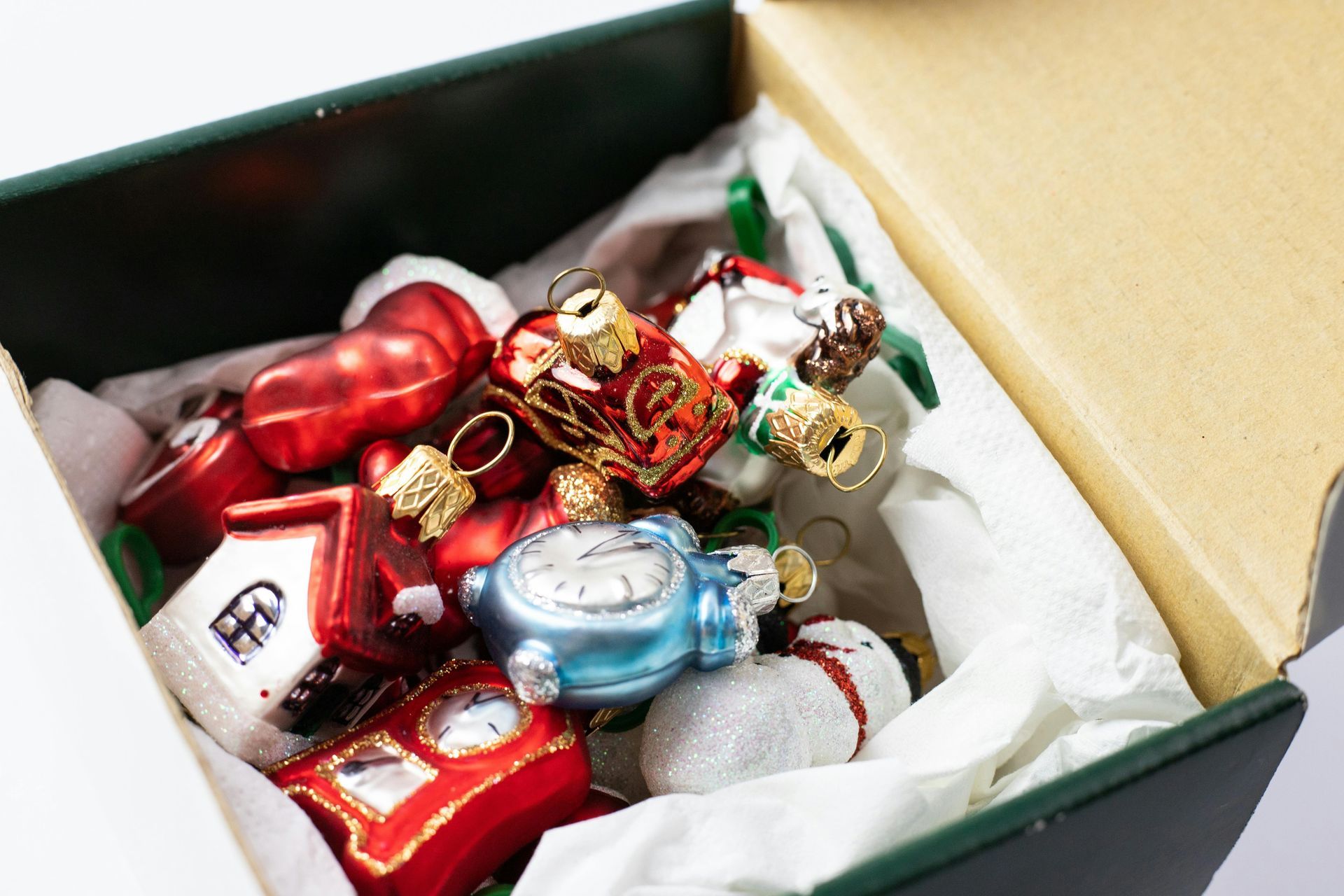 Box of colorful Christmas ornaments including a house, bell, and snowman.