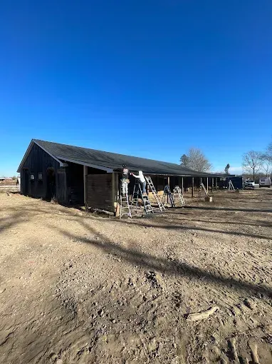 A large barn is sitting in the middle of a dirt field.