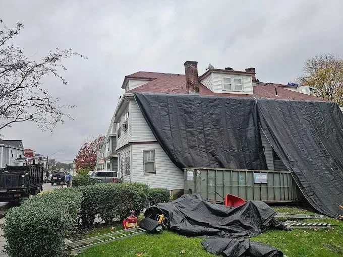 A large black tarp is covering the roof of a house.