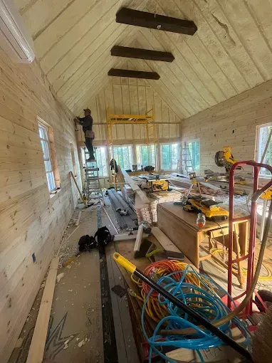 A man is standing on a ladder in a room with a lot of tools.