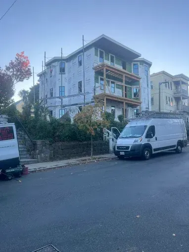 A white van is parked in front of a building under construction.