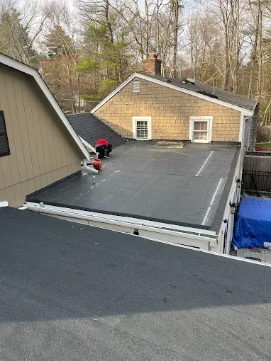 A black roof is being installed on the side of a house.