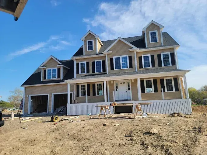 A large house is being built in a dirt field.