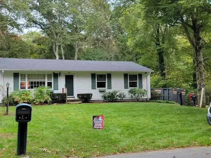 A white house with a black roof is for sale