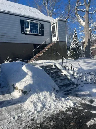 A house with stairs leading up to it is covered in snow.