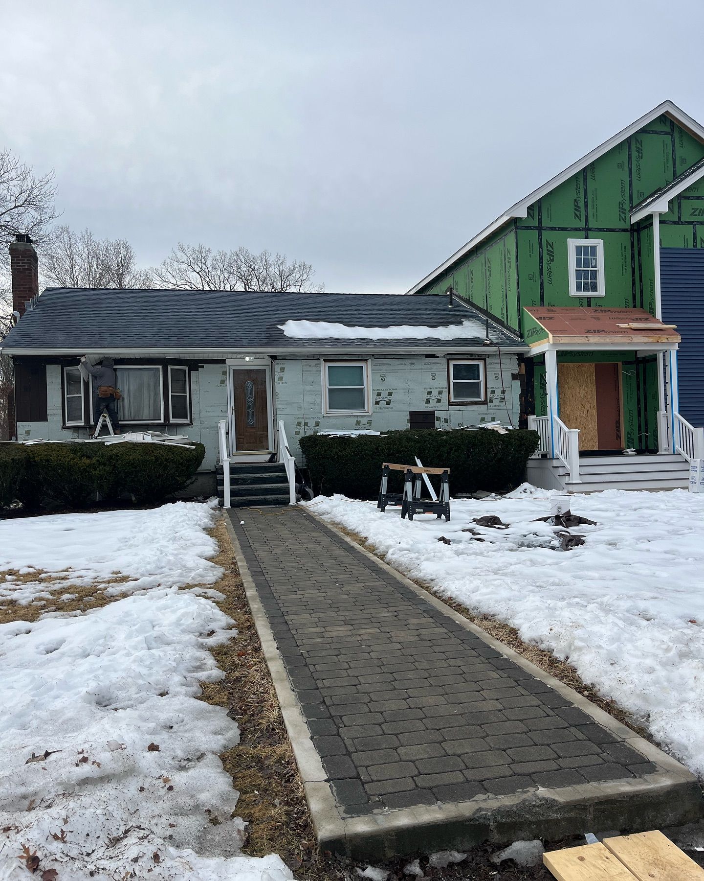 A house with snow on the ground and a walkway leading to it.