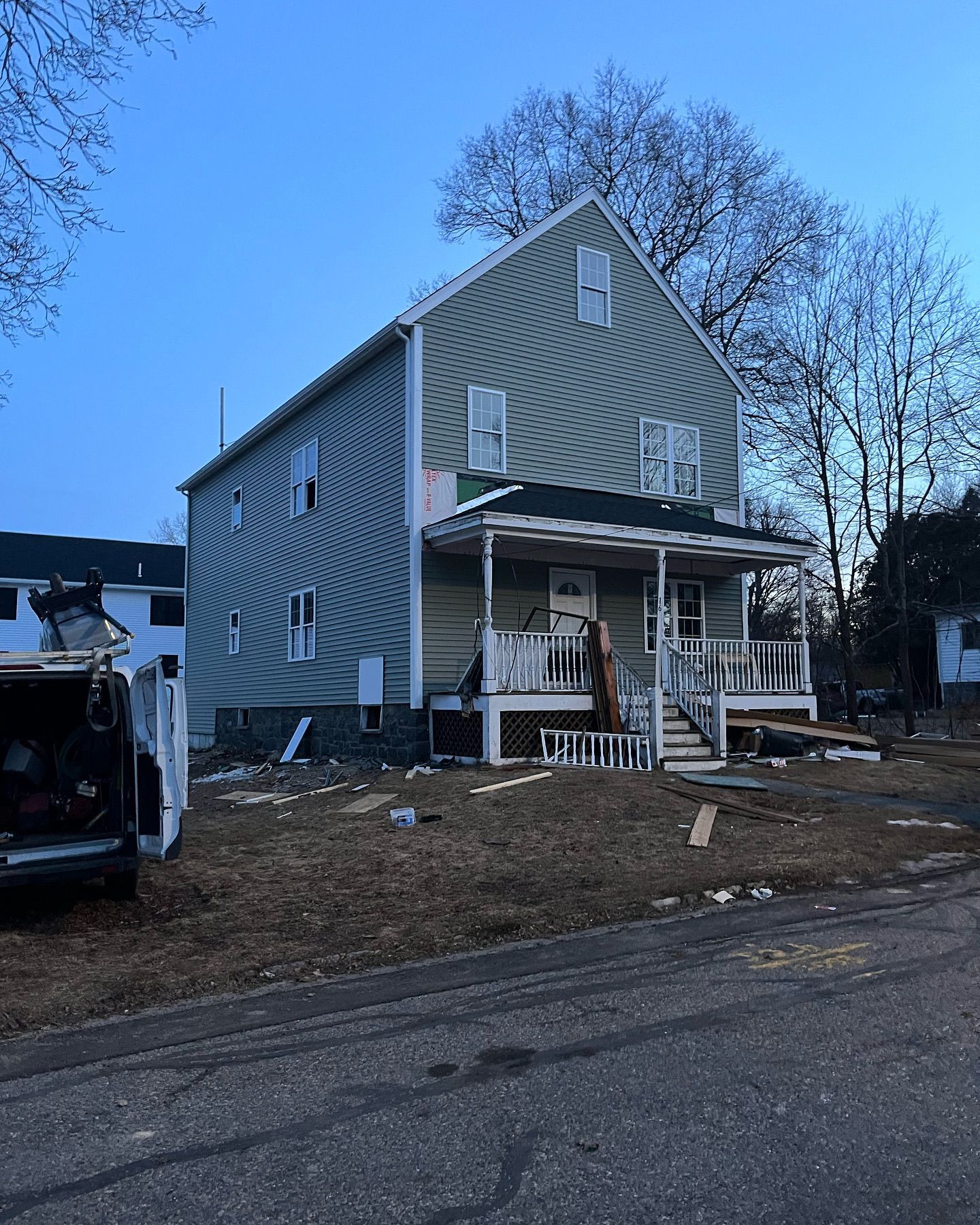 A large house with a porch and a truck parked in front of it.