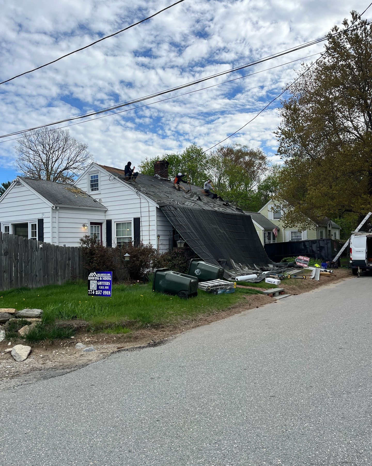 A house with a broken roof is sitting on the side of the road.