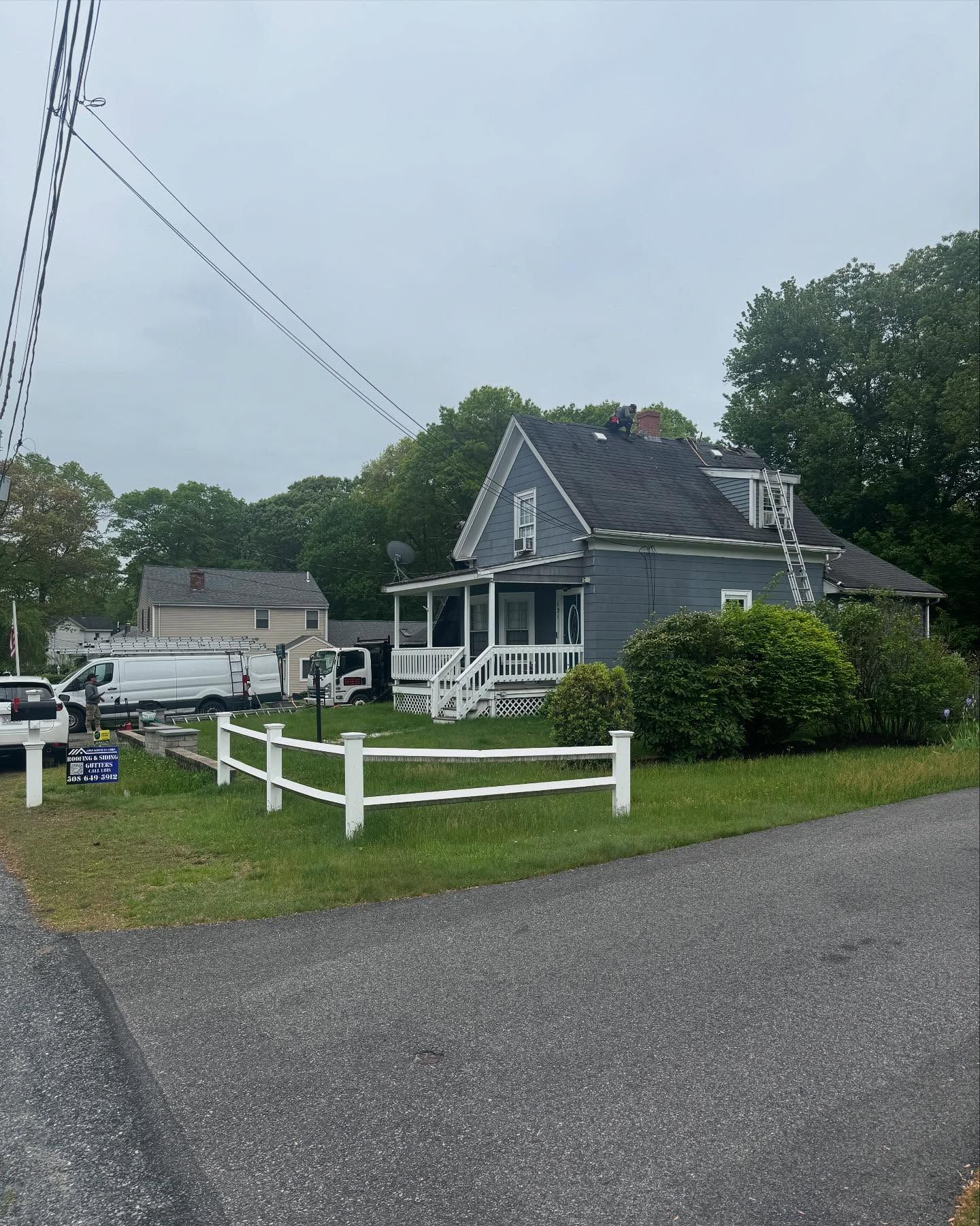 A gray house with a white fence in front of it.