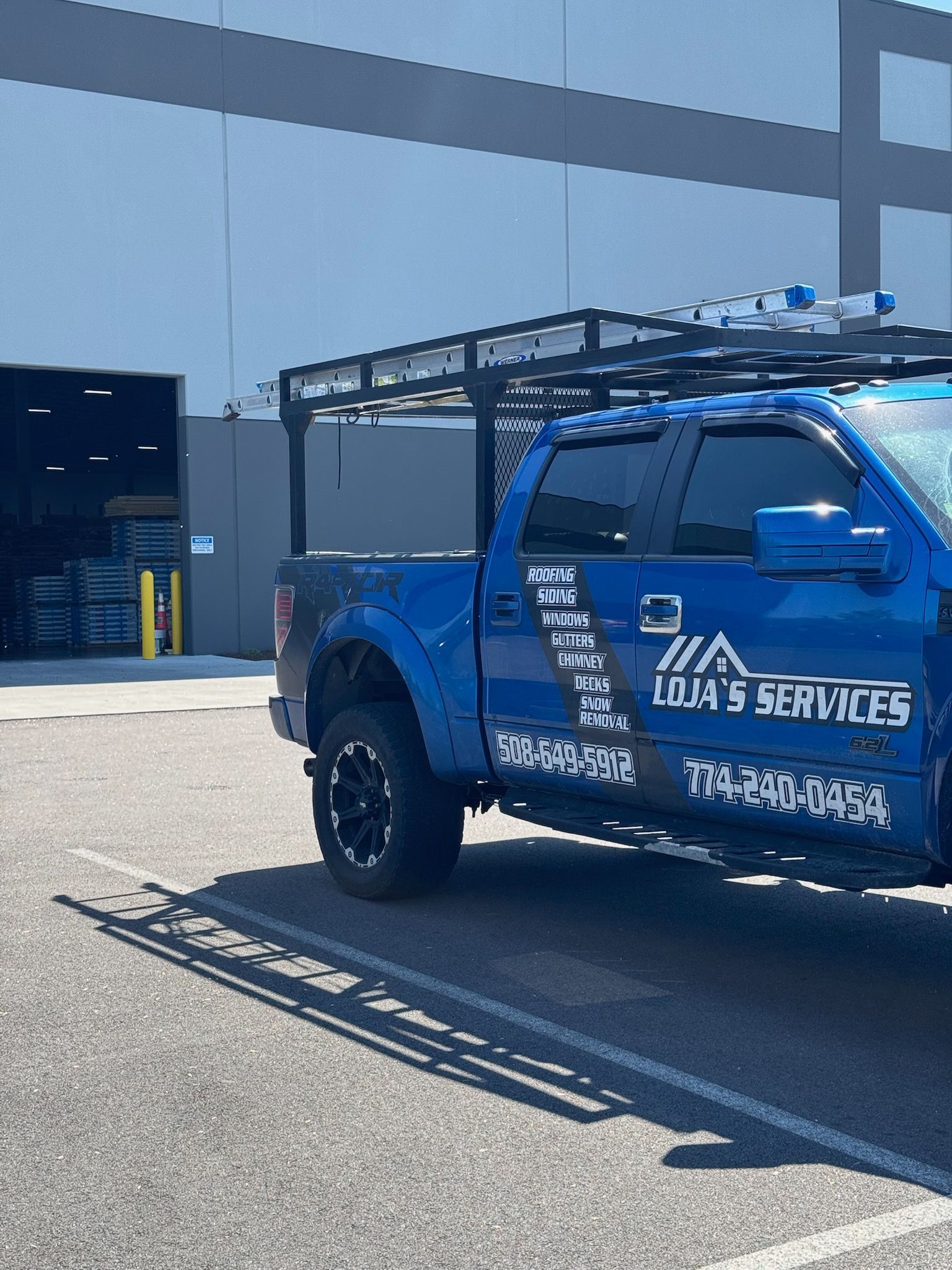 A blue truck is parked in a parking lot in front of a building.