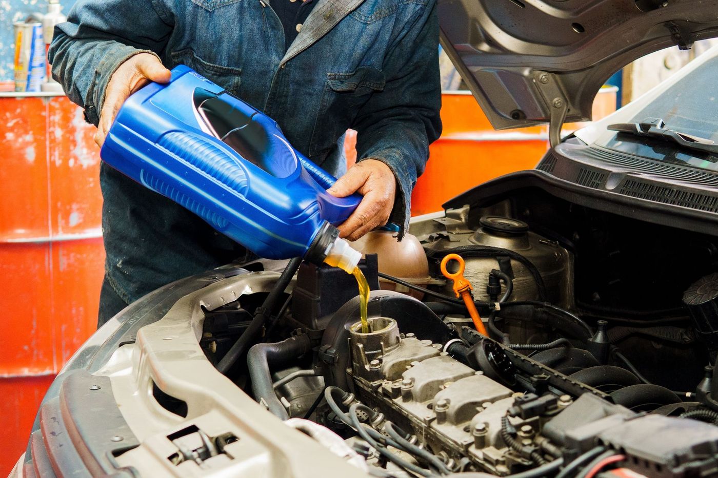A person is pouring oil into a car engine.
